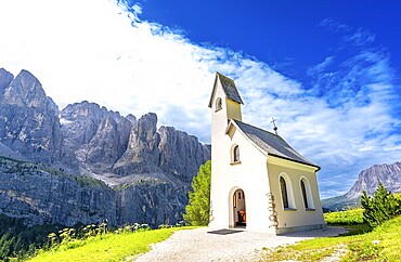 Scenic view of a charming church nestled in the italian dolomites, with the breathtaking peaks creating a stunning backdrop under a vibrant blue sky