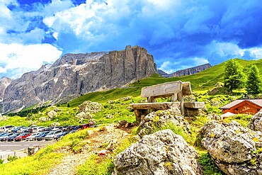 Weathered wooden bench inviting rest while offering breathtaking views of sella pass in the italian dolomites
