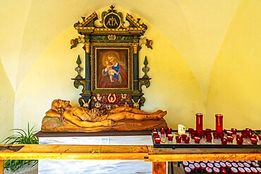 Reclining wooden statue of jesus christ and painting of madonna with child inside the santa maddalena church in val di funes, dolomites, italy