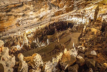 Tourists walking on illuminated footpath inside the famous postojna cave, a karst cave system near postojna, slovenia