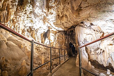 Tourists walking on a footpath and exploring the magnificent postojna cave in slovenia, a popular tourist attraction