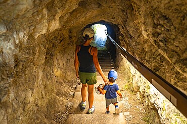 Mother and son walking up the stairs in a tunnel carved into the rock face at tolmin gorge in slovenia