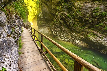 Scenic wooden walkway winds through vintgar gorge, showcasing stunning emerald waters and lush canyon walls in slovenia
