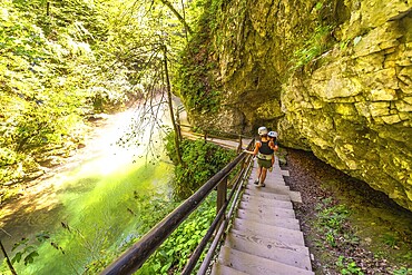Tourists wearing helmets are walking down wooden stairs along the radovna river in vintgar gorge, a popular tourist destination near bled, slovenia