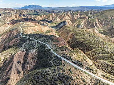 Winding road on a plateau, surrounded by colorful canyons and gorges, aerial view, Gorafe Desert, UNESCO Granada Geopark, Granada province, Andalusia, Spain, Europe