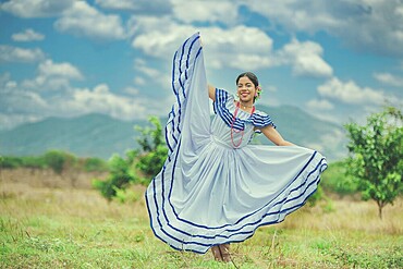 Young Nicaraguan woman in traditional folk costume in a field, smiling at camera