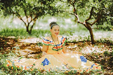 Happy girl in national folk costume sitting on the grass
