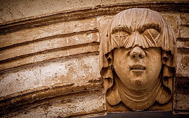 Gothic detail. Young woman portrait at the entrance of a 200 years old building in Ciutadella town, Menorca Spain