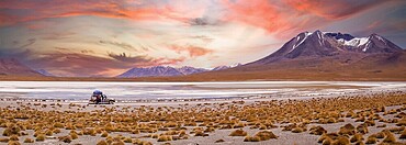 Amazing sky at sunset over Altiplano, Bolivia as an off-road vehicle is driving by