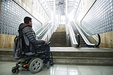 Rear View Of A Disabled Man On Wheelchair In Front Of Staircase