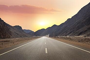 Sunrise over road through mountains in desert of Egypt