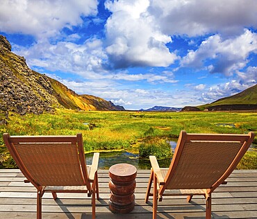 Two comfortable wooden chairs and small table stand for tired tourists. Volcanic summer tundra. Travel to Iceland in July