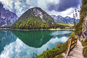 Magnificent Alpine lake Lago di Braies. Walking trail around the lake is fenced with wooden railings. The concept of environmental and hiking