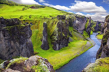 Magic beauty canyon in Iceland - Fyadrarglyufur. Steep cliffs, overgrown with green moss, surrounded by fast river with cold water