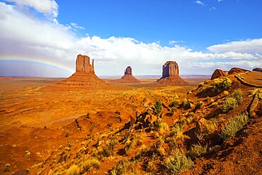 The USA. Magnificent rainbow across the sky. Monument Valley is unique geological formation. Huge masses of red sandstone - outliers on the Indian Navajo Reservation. Concept of photo tourism