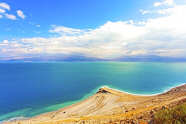 The smooth surface of the very salty sea water reflects the sky and clouds. Low winter clouds are reflected in the green sea water. Israel. Legendary Dead Sea