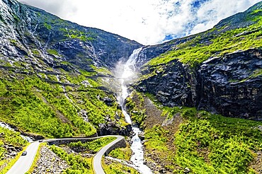 Trollstigen /Troll Staircase/ - the most popular tourist spot in Norway. The huge Stigfossen waterfall. The road serpentine meanders picturesquely on the green slopes of the canyon