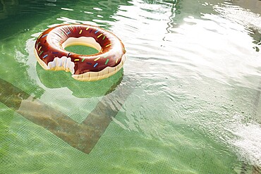 A swimming circle in the form of a bitten doughnut floats in the water of the pool.