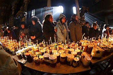 Blagoevgrad, Bulgaria - February 10, 2019: Worshippers light candles on jars with honey during a religious ritual marking the day of Saint Haralampi - the Orthodox patron saint of beekeepers - in the church of the Presentation of the Blessed Virgin