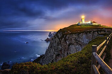 Farol do Cabo de Boca, Portuguese coast with a lit lighthouse at night