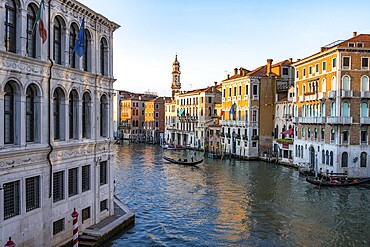 View of the Grand Canal with gondoliers at sunset, picturesque evening mood with palazzos on the canal and church tower of the Chiesa Parrocchiale dei Santi Apostoli, view from the Rialto Bridge, Venice, Veneto, Italy, Europe