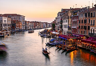 View of the Grand Canal with gondoliers at sunset, picturesque evening mood with illuminated palazzos on the canal, long exposure, view from the Rialto Bridge, Venice, Veneto, Italy, Europe