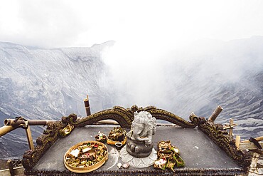 Traditional offerings and a statue on an altar with a misty volcano background, Bromo volcano, Sri Lanka, Asia