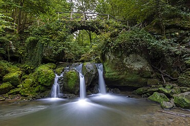 Cascade shooting pond, waterfall under small pedestrian bridge, Mullerthal Trail, Waldbillig, Luxembourg, Europe