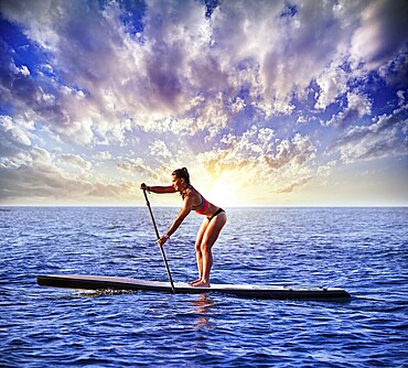 SUP Stand up Surf girl with paddle in a blue ocean sea
