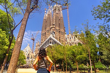 Young woman admiring the impressive sagrada familia basilica, a unesco world heritage site, during a sunny summer day in Barcelona, Catalonia, Spain
