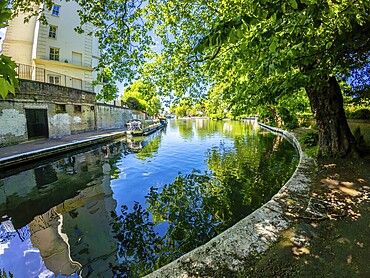Calm waters reflecting buildings and lush trees along little venice canal in london, offering a peaceful urban oasis