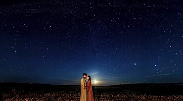 A couple under a vast starry night sky, evoking a sense of romance and wonder