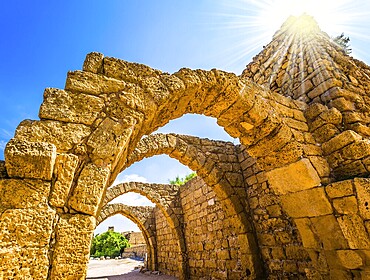 Dazzling spring sun illuminates the ancient Mediterranean port. The remains of the covered arcades in Caesarea. Israel. Concept of phototourism and historical tourism