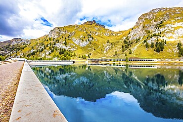 Mountain Lake Lago di Fedaia, Dolomites. Glacial lake with clear cold water. Powerful dam blocked the lake. The concept of ecological and extreme tourism