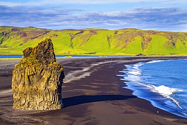 Cape Dyrholaey. Travel to the fabulous island of Iceland. Giant lonely rock - Palm on a black volcanic sand beach Reinisfjara. The concept of active, extreme and photo tourism