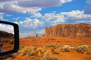 Monument Valley is a unique geological formation. The USA. Huge masses of red sandstone - outliers on the Navajo Indian Reservation. Reflection in a car mirror. The concept of photo tourism