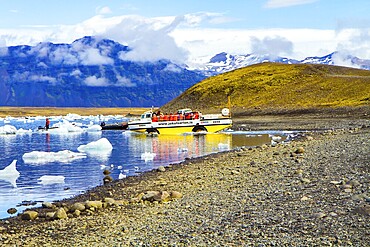 ICELAND, SCAFTAFETL PARK, ICE LAGOON JOKULSAURLOUN - July 10, 2014: Yellow boat for tourists. The icebergs and ice floes reflected in the water. The concept of northern and photo tourism