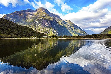 The mountains are reflected in the smooth water of the fjord. The most famous and picturesque fjord is Milford Sound. Fiordland park. New Zealand. South Island