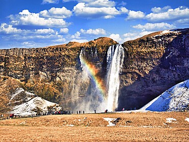 Seljalandsfoss, a majestic and powerful waterfall in Iceland in a sunny spring day with a raibow