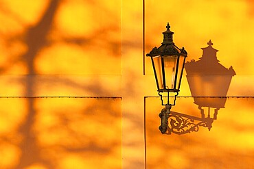 Detail of retro street light on the wall at sunset. Prague, Czech Republic