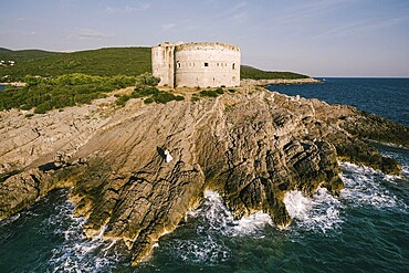 Bride and groom stand on the rocks near the fortress by the sea. Aerial view.