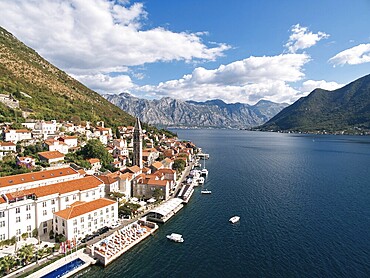 Swimming pool and private beach on the shore of the Bay of Kotor overlooking ancient houses. Perast, Montenegro. Drone.