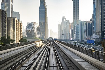 Dubai, UAE - 11.3.2022: Dubai Metro rail with skyscrapers and Museum of the Future in Dubai in the frame. Dubai Cityscape skyline with modern urban transit system