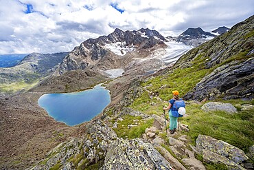 Mountaineer on hiking trail in dramatic high mountain landscape, view of mountains with mountain lake Vogelhüttensee and glacier Übeltalferner, Stubai Alps, South Tyrol, Italy
