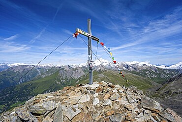 Böses Weibl summit with summit cross and colourful prayer flags, view of picturesque mountain landscape with snow-covered summit of the Großglockner, Wiener Höhenweg, Schober group, Hohe Tauern National Park, Carinthia, Austria