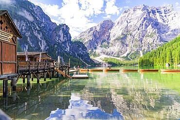 Wooden huts on the lakeshore against a majestic mountain backdrop and calm waters, Lake Braies, South Tyrol, Dolomites, Italy