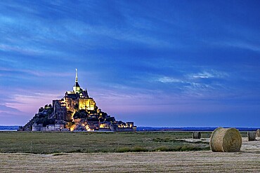 Mont Saint-Michel at dusk, illuminated with straw bales in the foreground, Mont Saint Michel in Normandy, France