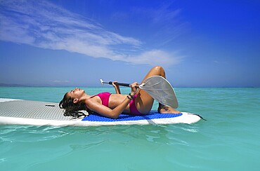 Girl relaxed lying on paddle surf board SUP relaxed in summer