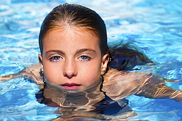Beautiful blue eyes kid girl at the pool with face in water surface