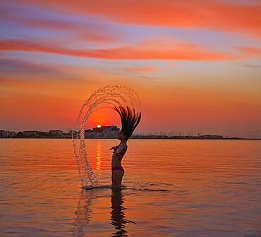Girl flipping hair flip at sunset beach in orange sky